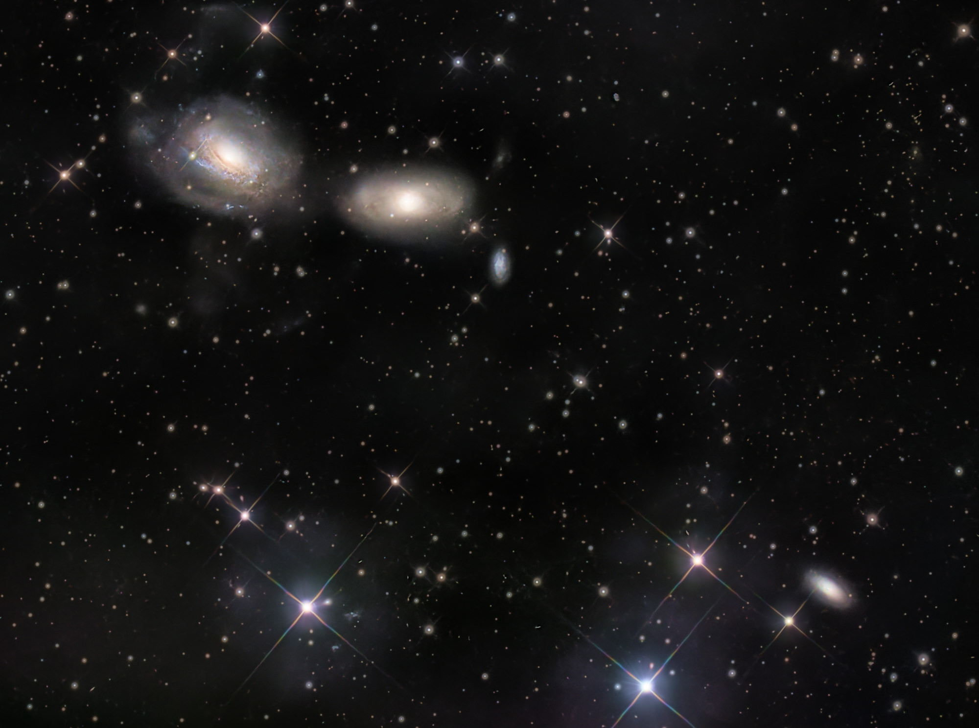Die gewundenen Spiralarme von NGC 3169 (links) wurden durch die gravitative Wechselwirkung mit der benachbarten Galaxie NGC 3166 zu ausladenden Gezeitenschweifen herausgezogen. Die beiden Galaxien werden am Ende zu einer verschmelzen.